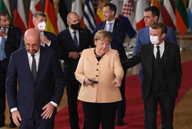 German Chancellor Angela Merkel surrounded by European Council President Charles Michel and French President Emmanuel Macron on the first day of the European Union summit in Brussels on October 21, 2021.