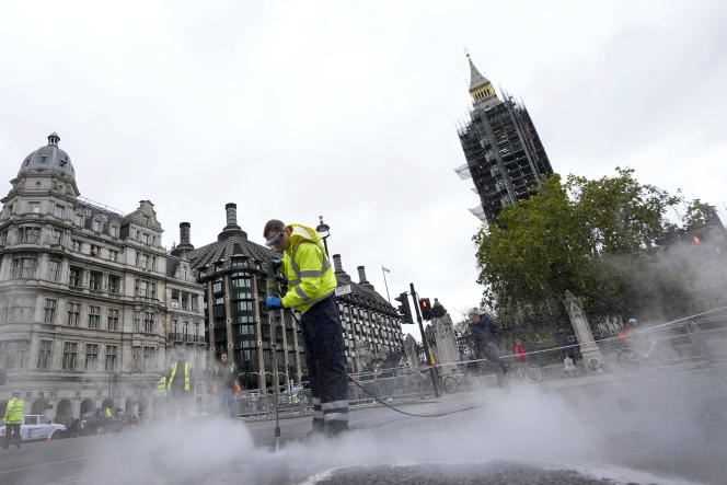 A cleaner removes glue spilled from the road outside Houses of Parliament after Insulate Britain protesters stuck to the tarmac in London on November 4, 2021.