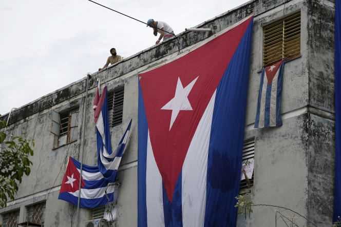 Men hold out Cuban flags in front of the windows of the home of opponent Yunior Garcia Aguilera, November 14, 2021, in Havana, to prevent him from communicating with the outside.