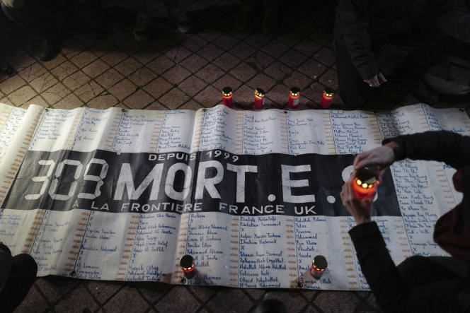 Activists and members of migrant rights associations light candles in front of a banner reading 