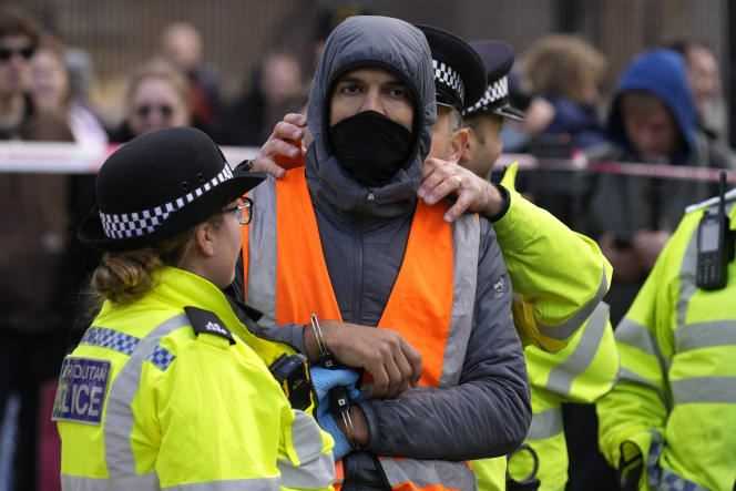 An Insulate Britain activist is arrested after being lifted off the roof of a police van outside Parliament in London on November 4, 2021.