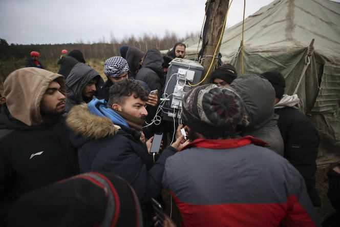 Migrants charge their smartphones outside a camp set up by Belarusian soldiers and border rescuers near Grodno, Belarus, November 13, 2021.