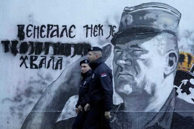 Police officers stand guard in front of a mural depicting former military leader Ratko Mladic in Belgrade on November 9, 2021.