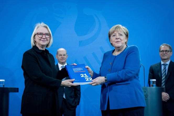 Economist Monika Schnitzer (left) hands outgoing German Chancellor Angela Merkel (right) the annual report of the “Council of Wise Men” in Berlin on November 10, 2021.