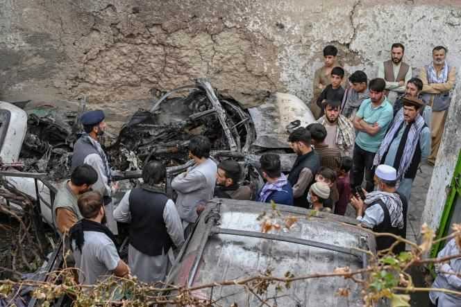 Afghans are gathered next to a damaged vehicle in the aftermath of a US drone strike in Kabul on August 30, 2021.