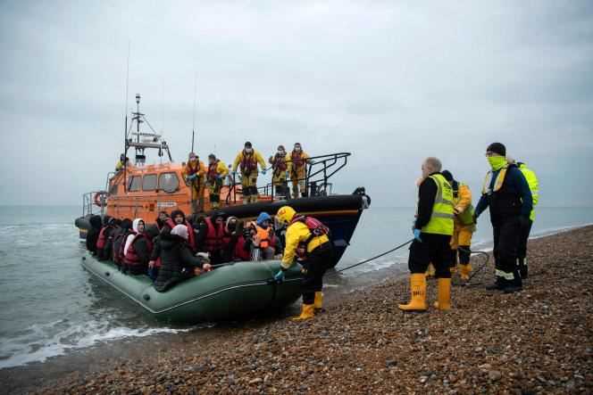Migrants disembark from a Royal National Lifeboat Institution (RNLI) lifeboat at a beach in Dungeness, on the south-east coast of England, on November 24, 2021, after being rescued while crossing the Handle.  On the same day, at least twenty migrants died trying to cross the Channel from Calais to England.