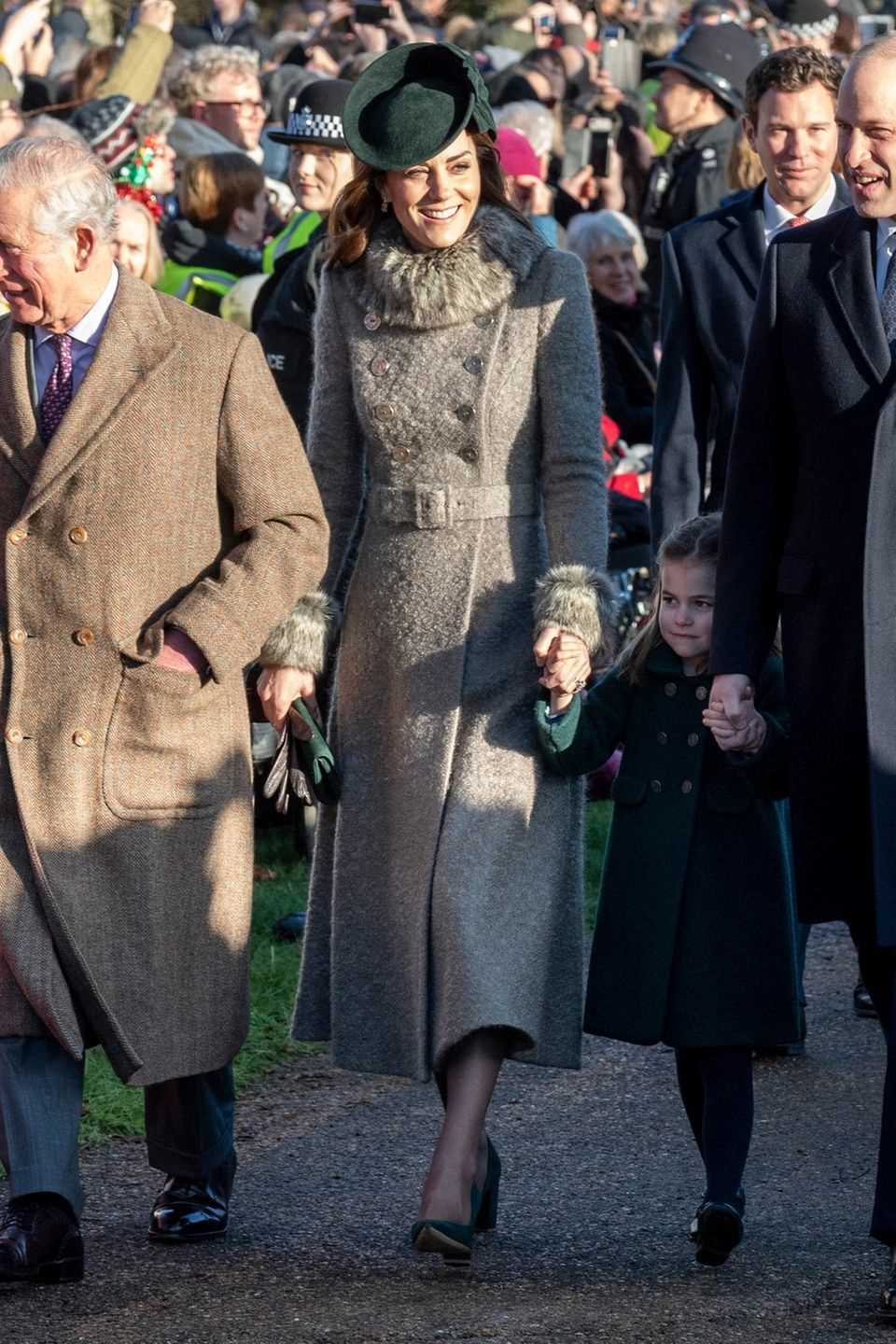 For the Christmas service in Sandringham, Duchess Kate has chosen an elegant and cozy winter look: She is wearing a coat by Catherine Walker with faux fur elements.  A waist belt emphasizes your slim silhouette.  Kate's chic suede pumps and clutch are from Emmy London and perfectly match the color of her fascinator ...