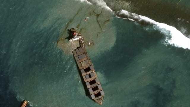 The freighter can be seen from above, oil is running into the sea.