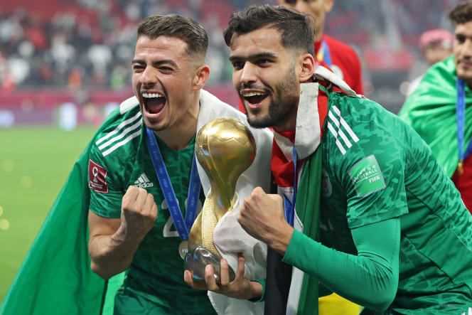 Algerian defenders Ilyes Chetti (left) and Mohamed Tougai pose with the Arab Cup trophy at Al-Bayt stadium in Al-Khor, northeastern Qatar, Saturday, December 18, 2021.