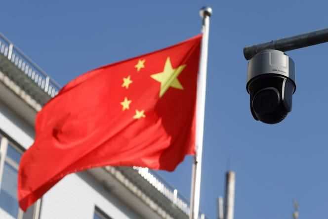 A surveillance camera overlooking a street is pictured next to a nearby Chinese flag waving in Beijing, China on November 25, 2021.