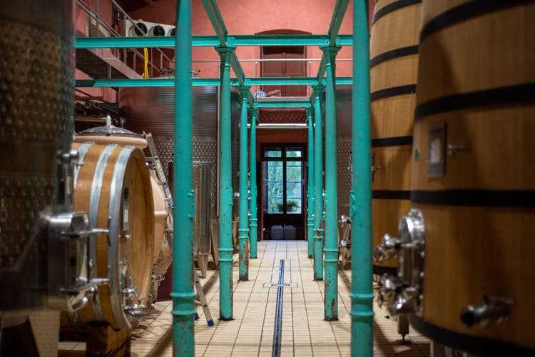 Steel tanks and wooden barrels for fermentation in the Scacciadiavoli wine cellar.
