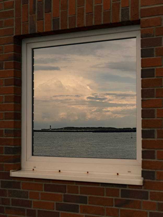 The nearby dune is reflected in the window of a house on Heligoland.