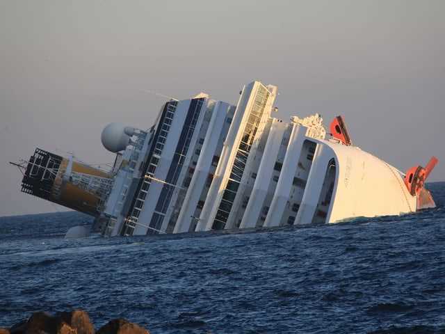 The Costa Concordia, tilted to one side and half sunken, in front of Giglio.