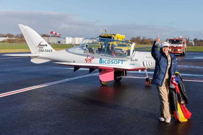 Zara Rutherford poses in front of the plane that took her around the world after landing.