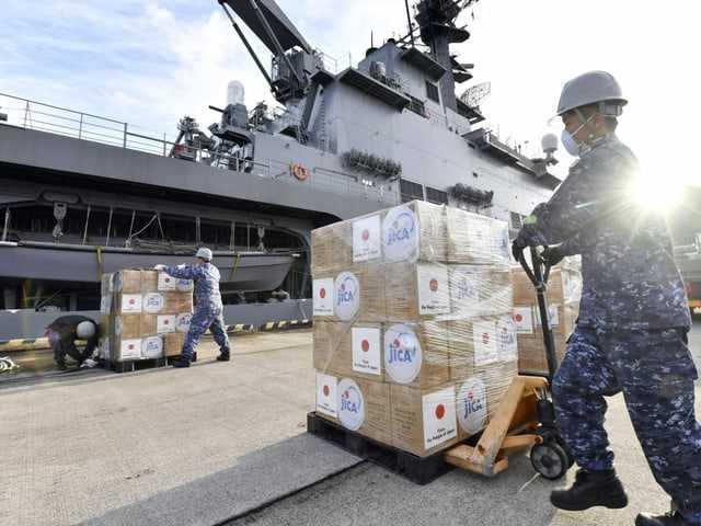 A Japanese loads relief supplies into a military ship.