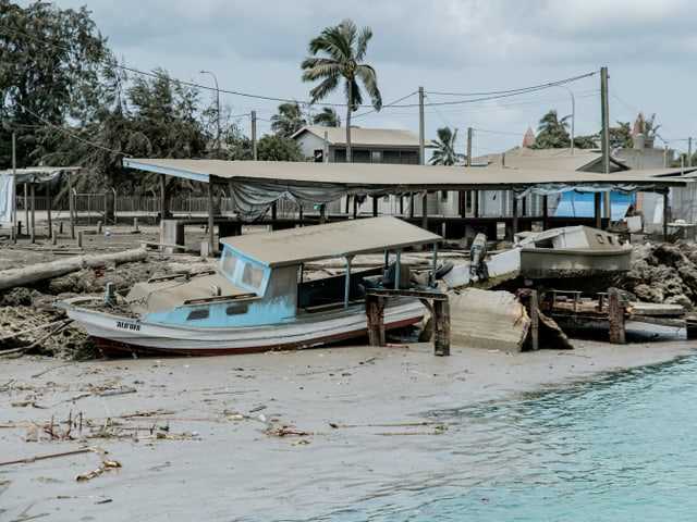 Destroyed houses and a boat on dry land can be seen.