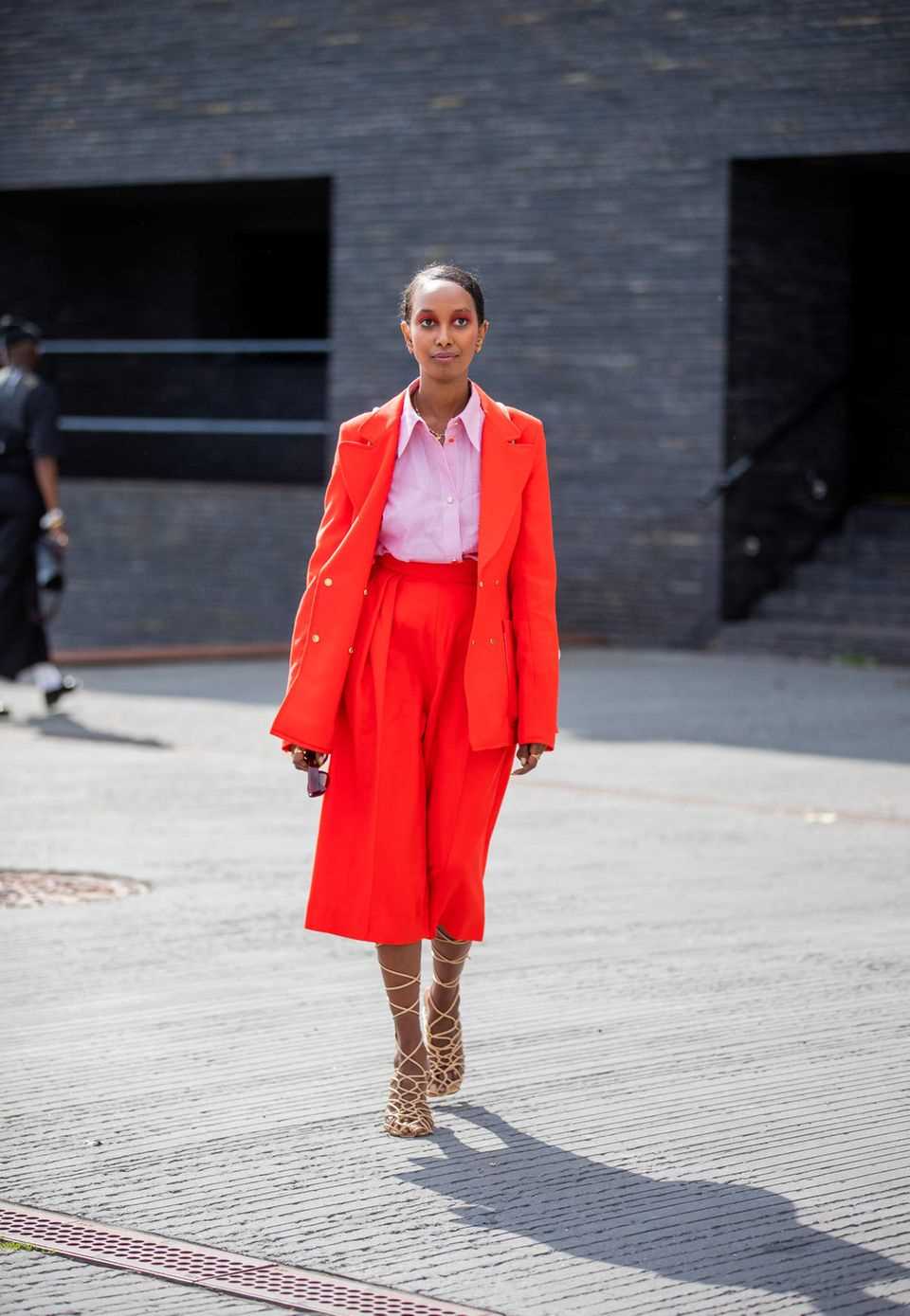 A woman in a red two-piece suit and pink blouse at Copenhagen Fashion Week 2021