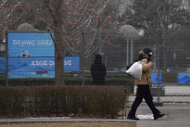 A man walks past the Beijing Winter Olympics media center January 30, which is fenced off from the public. 