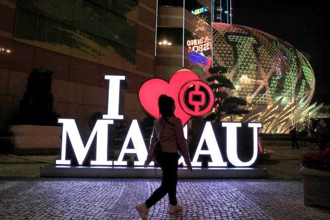 A typical Macau night scene - a passer-by in front of a bank branch, a hotel and a casino. 