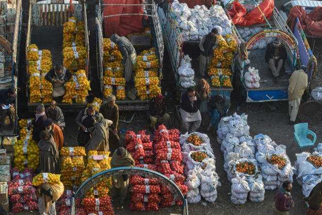 Wholesale fruit vendors deal with customers and their suppliers at a market in Lahore on December 29, 2021.