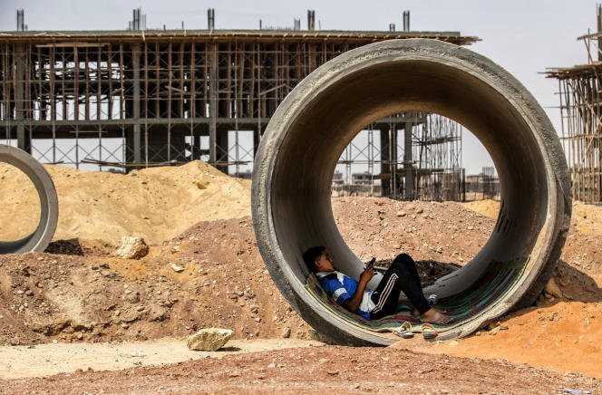A worker rests inside a concrete tube while shielding himself from the sun at a construction site of Egypt's 'new administrative capital' megaproject, 45 kilometers east of Cairo, on 3 August 2021.