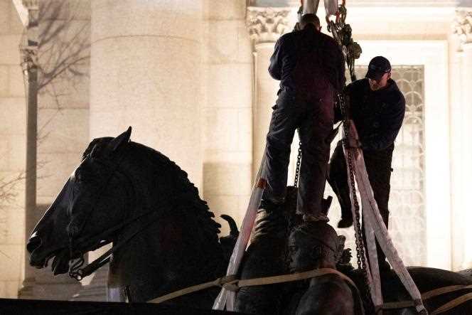 Workers secure the statue of Theodore Roosevelt after removing it from the entrance to the Museum of Natural History in New York on January 20, 2022.