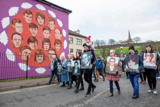 The procession, led by relatives of the victims, passes in front of a mural paying tribute to the victims of Bloody Sunday, Sunday January 30, 2022, in Derry.