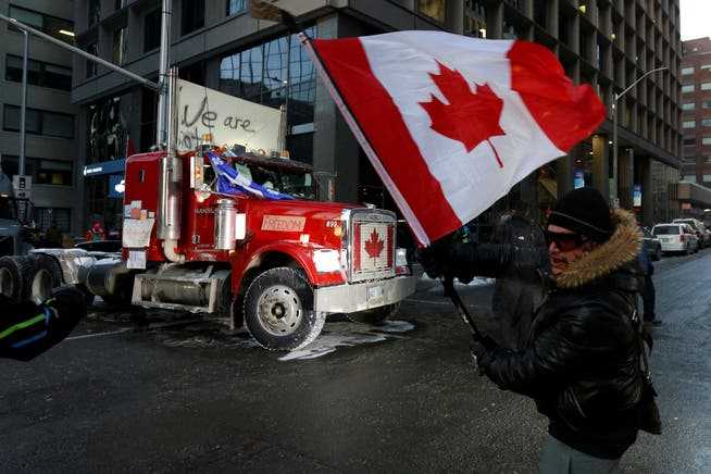 A person waves a Canadian flag in front of a truck, as truckers and supporters continue to protest coronavirus disease (COVID-19) vaccine mandates, in Ottawa, Ontario, Canada, February 5, 2022. REUTERS/Lars Hagberg