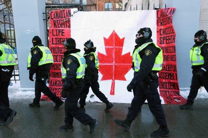 Police in front of a Canadian flag near Parliament in Ottawa during protests against health measures on February 7, 2022.
