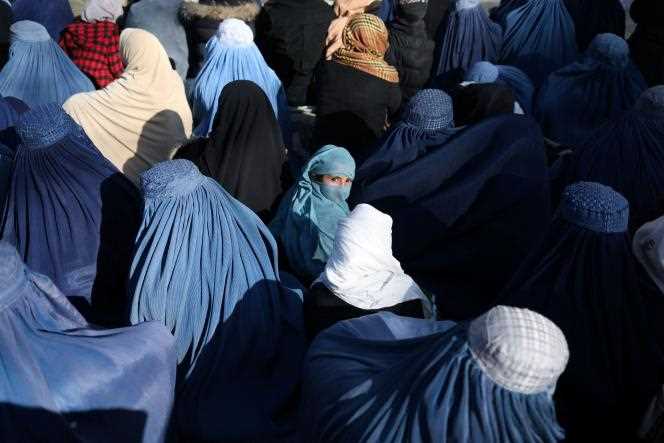 An Afghan girl sits in front of a bakery in the crowd of Afghan women waiting to receive bread in Kabul, Afghanistan, January 31, 2022.