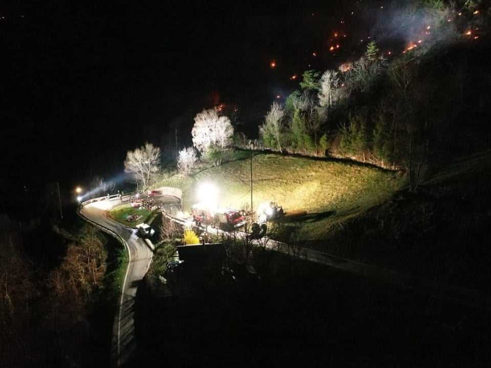 Rescue workers can be seen at night on a bend in the road.