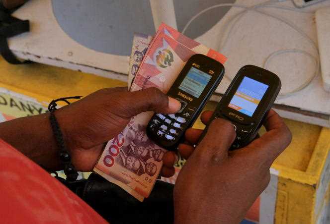 A trader uses phones for a transaction, in Accra on March 26, 2022.