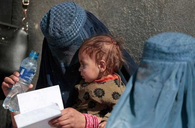 An Afghan woman and her child wait to receive aid next to a United Nations High Commissioner for Refugees distribution center near Kabul on October 28, 2021.