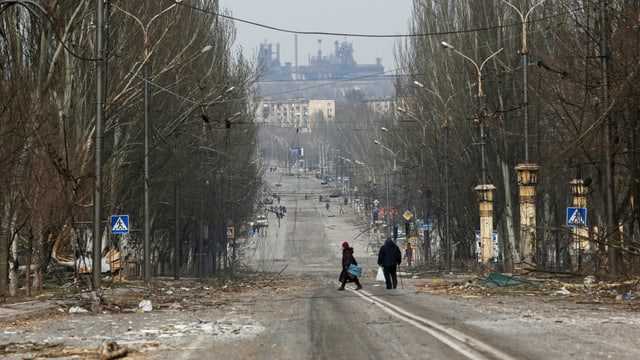 Menschen auf einer Strasse voller Trümmer in Mariupol.