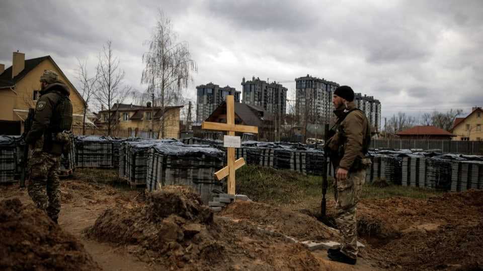 Ukrainian soldiers in front of a grave where, according to local residents, a resident of Bucha who was killed by Russians lies.