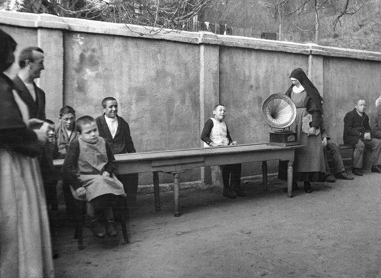 A nun plays music on a gramophone to a child.  Presumably Marsens Sanatorium and Nursing Home, Freiburg, 