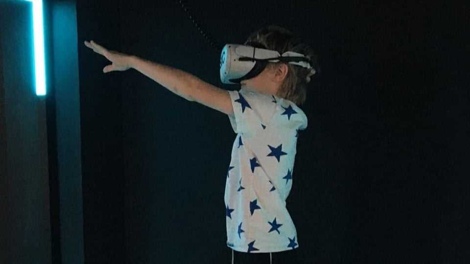 A child wears VR glasses and stretches out his hand