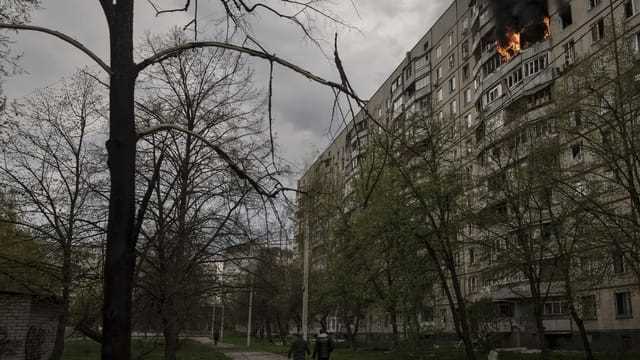 Menschen in der Nähe einer brennenden Wohnung in Charkiw am 22. April 2022. 