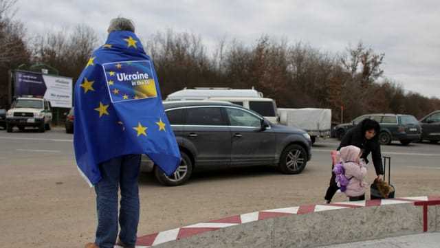 Mann mit EU Flagge steht an der Grenze