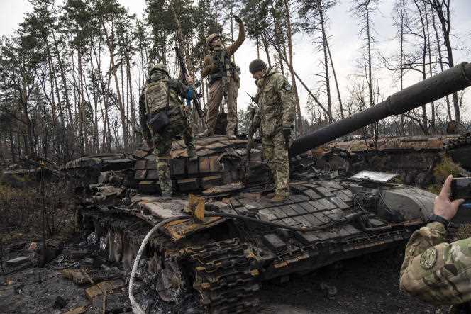 Ukrainian soldiers take photos perched on the wreckage of a Russian tank, in the suburbs of kyiv, March 31, 2022.