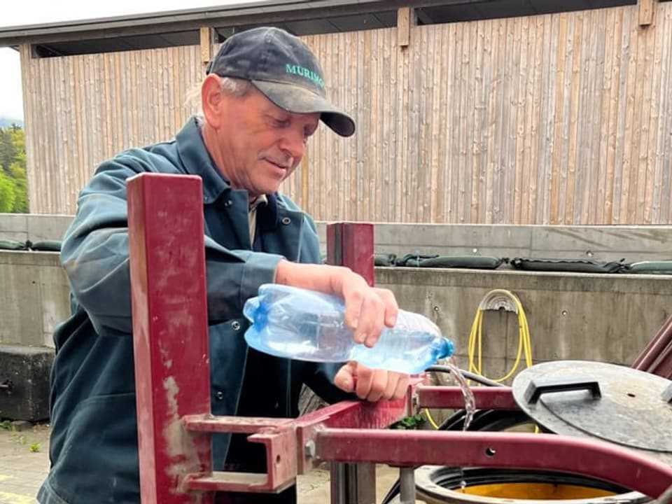 Man pours water bottle into tank.