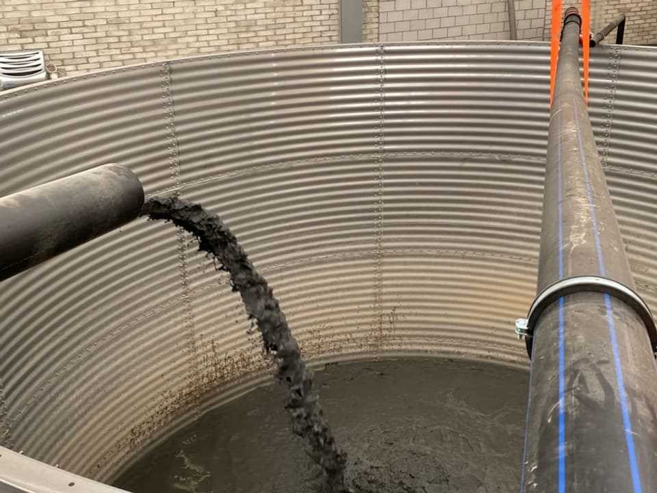 A mixture of mud and water flows into a huge container.