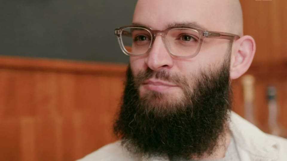 Man with glasses, beard and bald head.