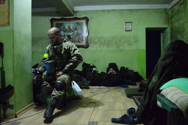 A soldier from the Chartiya Battalion charges his mobile phone in the basement of a church in Ruska Losowa.