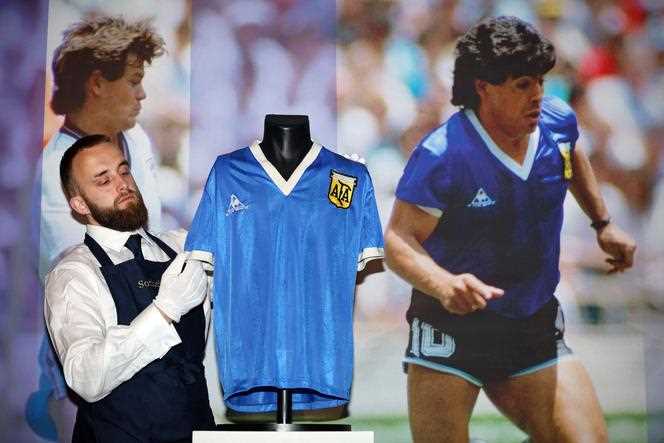 On April 20, 2022, a Sotheby's employee adjusts the jersey worn by Diego Maradona during the 1986 World Cup. (Photo ADRIAN DENNIS / AFP)