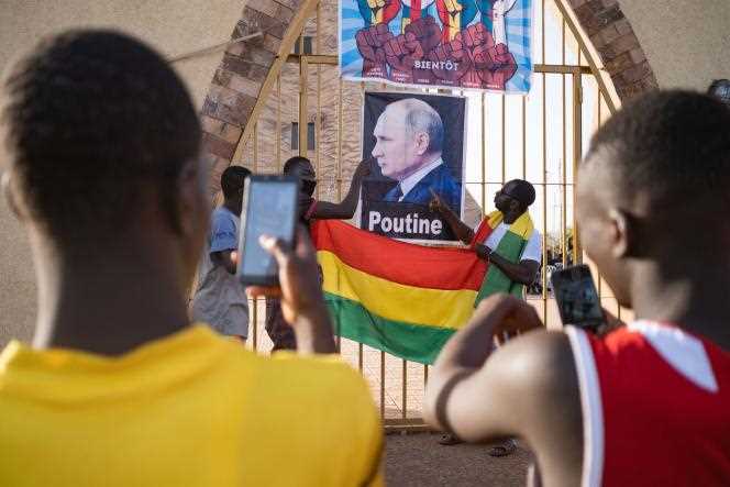 Young people take pictures in front of a poster of Russian President Vladimir Putin, during the demonstration led by the Yerewolo movement against the French military presence in Mali, Place de la Tour de l'Afrique, in Bamako, February 4, 2022.