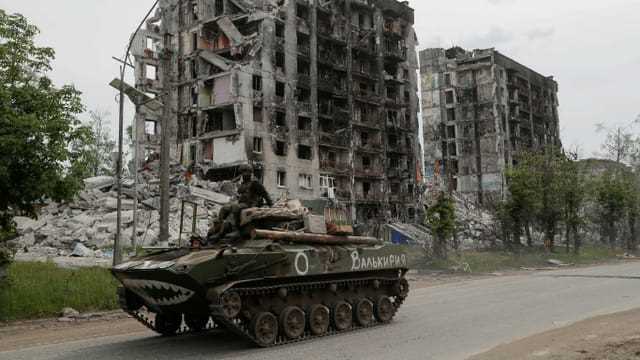 Panzer der pro-russischen Treppen in Popasna vor zerstörtem Haus