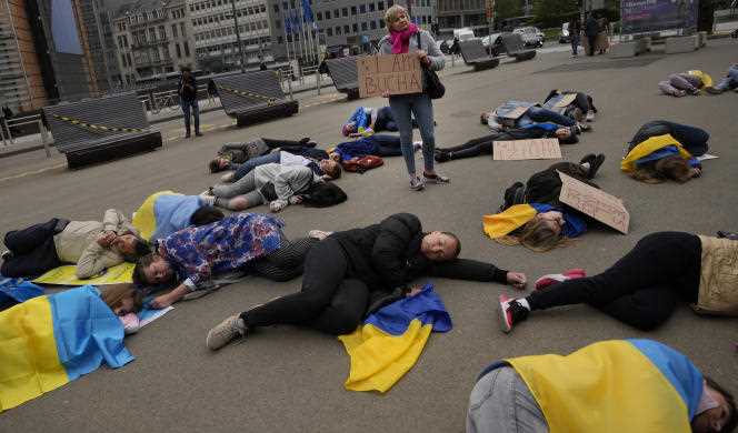In Brussels on April 29, 2022, demonstrators wrap themselves in Ukrainian flags and demand that European leaders stop buying Russian gas and oil.