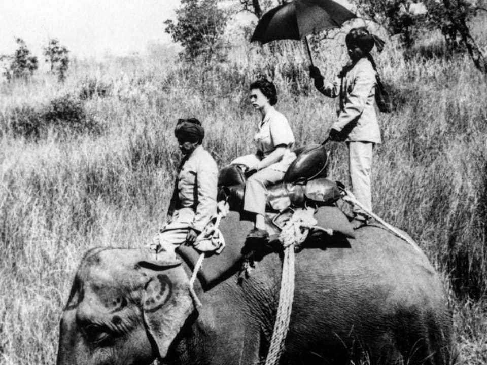 Black and white photo: woman with two uniformed men on an elephant.