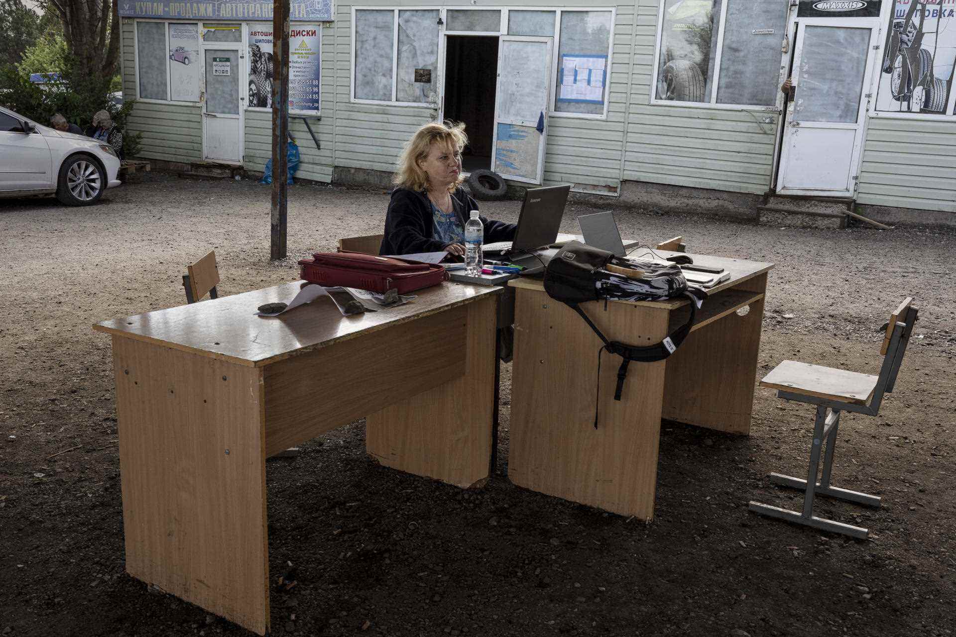 Olga registers displaced persons wishing to return to the occupied territories to register in a file, in a parking lot where Ukrainians will wait for their departure to the occupied areas, near Zaporizhia, Ukraine, on June 15, 2022. 